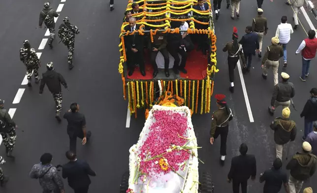 Security officials and others walk with the hearse carrying the body of former Indian Prime Minister Manmohan Singh towards the cremation site in New Delhi, India, Saturday, Dec. 28, 2024. (AP Photo)