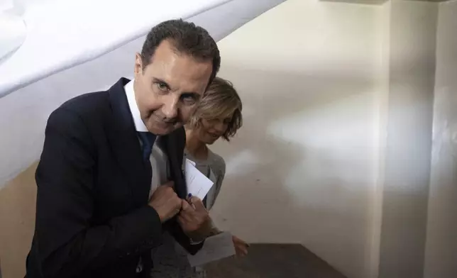 FILE - Syrian President Bashar Assad and his wife Asma prepare to vote at a polling station during the presidential elections in the town of Douma, in the eastern Ghouta region, near the Syrian capital Damascus, Syria, May 26, 2021. (AP Photo/Hassan Ammar, File)