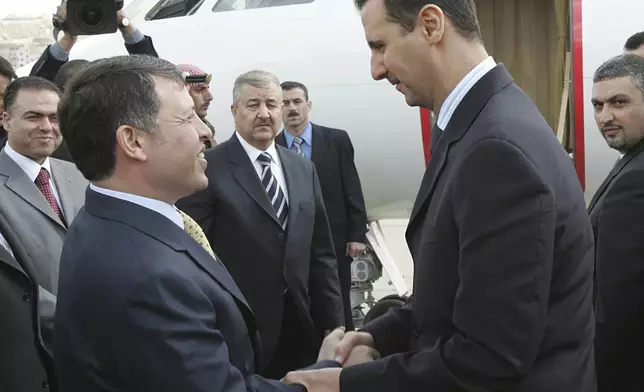 FILE - Jordan's King Abdullah II, left, shakes hands with Syrian President Bashar Assad, as he sees him off at Marka military airport in Amman, Jordan, Feb. 2, 2005. (AP Photo/Hussein Malla, File)