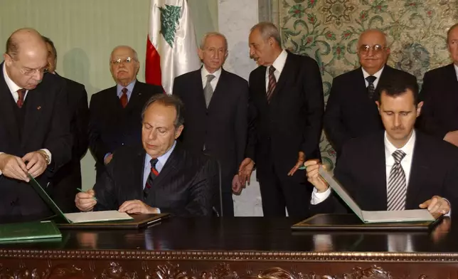FILE - Lebanese President Emile Lahoud, left, and his Syrian counterpart Bashar Assad sign documents during a meeting in Damascus, Syria, March 7, 2005. (AP Photo, File)