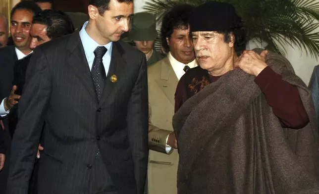 FILE - In this March 22, 2005 file photo, Syrian President Bashar Assad, left, talks to Libyan leader Moammar Gadhafi prior the 17th League of Arab States' summit in Algiers. (AP Photo/Nabil, File)