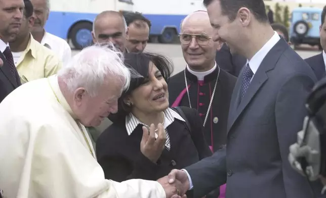 FILE - Syrian President Bashar Assad, right, shakes hands with Pope John Paul II before the Pontiff boards a plane after a four-day visit to Syria in Damascus, May 8, 2001. (AP Photo/Enric Marti, File)