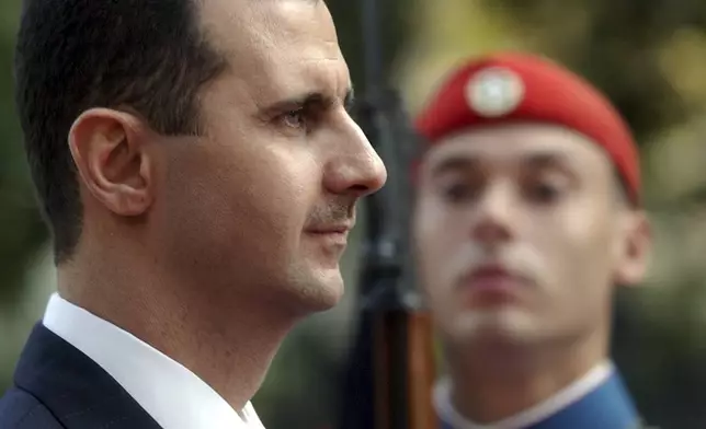 FILE - Syrian President Bashar Assad reviews the presidential guard during the welcoming ceremony in Athens, Dec. 15, 2003. (AP Photo/Petros Giannakouris, File)