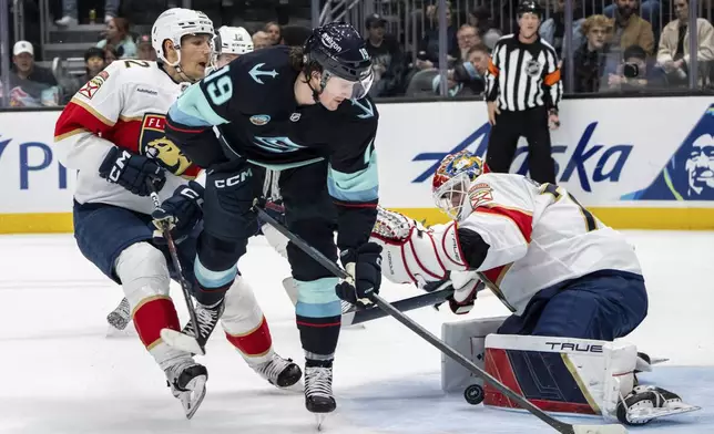 Florida Panthers goalie Sergei Bobrovsky, right, stops a shot by Seattle Kraken forward Jared McCann, center, during an NHL hockey game, Tuesday, Dec. 10, 2024, in Seattle. The Panthers won 2-1 in a shootout. (AP Photo/Stephen Brashear)