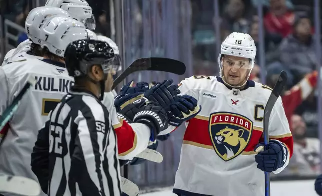 Florida Panthers forward Aleksander Barkov (16) is congratulated by teammates on the bench after scoring a goal during the second period of an NHL hockey game against the Seattle Kraken, Tuesday, Dec. 10, 2024, in Seattle. (AP Photo/Stephen Brashear)