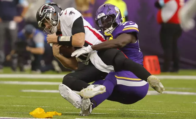 Atlanta Falcons quarterback Kirk Cousins is sacked by Minnesota Vikings linebacker Jamin Davis, right, during the first half of an NFL football game, Sunday, Dec. 8, 2024, in Minneapolis. (AP Photo/Bruce Kluckhohn)