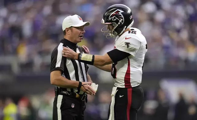 Atlanta Falcons quarterback Kirk Cousins talks with referee Alex Kemp, left, during the first half of an NFL football game against the Minnesota Vikings, Sunday, Dec. 8, 2024, in Minneapolis. (AP Photo/Abbie Parr)
