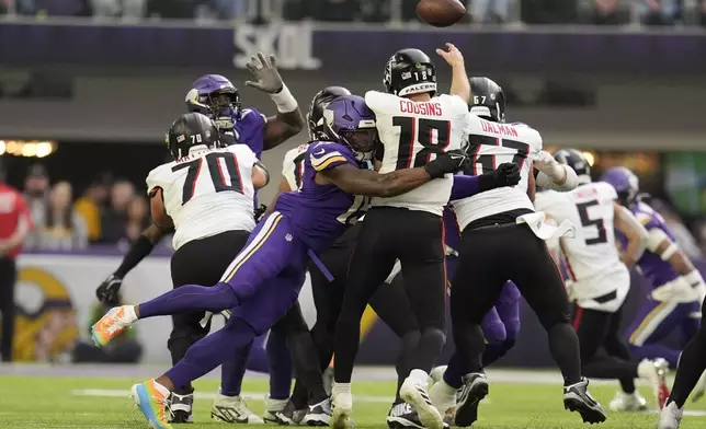 Atlanta Falcons quarterback Kirk Cousins (18) is hit by Minnesota Vikings linebacker Dallas Turner (15) while throwing a pass during the first half of an NFL football game, Sunday, Dec. 8, 2024, in Minneapolis. (AP Photo/Abbie Parr)
