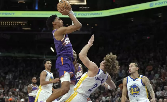 Golden State Warriors guard Brandin Podziemski (2) draws the offensive foul on Phoenix Suns center Oso Ighodaro during the first half of an NBA basketball game, Saturday, Nov. 30, 2024, in Phoenix. (AP Photo/Rick Scuteri)