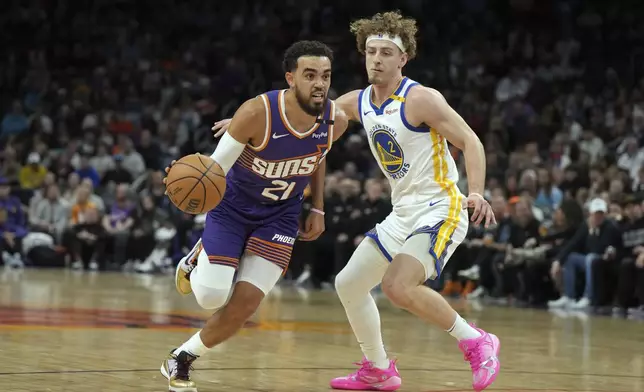 Phoenix Suns guard Tyus Jones (21) drives past Golden State Warriors guard Brandin Podziemski during the first half of an NBA basketball game, Saturday, Nov. 30, 2024, in Phoenix. (AP Photo/Rick Scuteri)