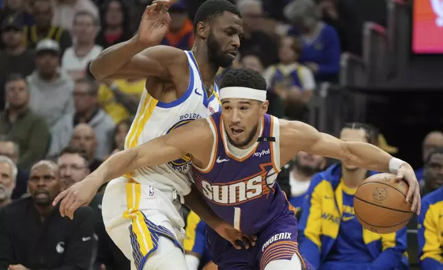 Phoenix Suns guard Devin Booker (1) drives around Golden State Warriors forward Andrew Wiggins during the first half of an NBA basketball game, Saturday, Nov. 30, 2024, in Phoenix. (AP Photo/Rick Scuteri)