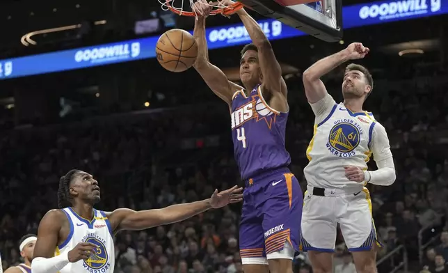 Phoenix Suns center Oso Ighodaro (4) dunks between Golden State Warriors guard Moses Moody and center Quinten Post (21) during the first half of an NBA basketball game, Saturday, Nov. 30, 2024, in Phoenix. (AP Photo/Rick Scuteri)