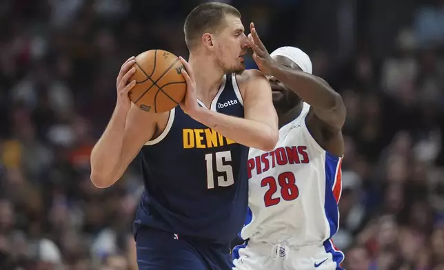 Denver Nuggets center Nikola Jokic, left, looks to pass the ball as Detroit Pistons center Isaiah Stewart defends in the first half of an NBA basketball game Saturday, Dec. 28, 2024, in Denver. (AP Photo/David Zalubowski)