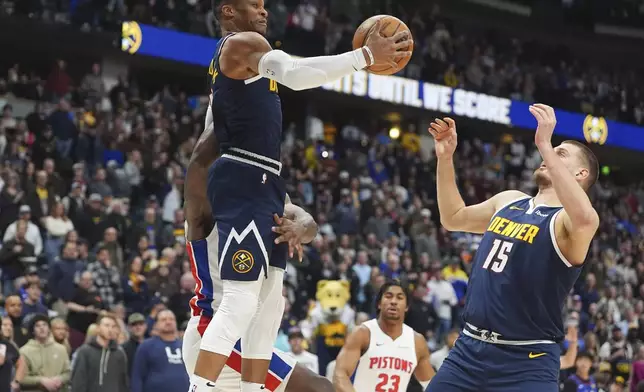 Denver Nuggets guard Russell Westbrook, front left, pulls in a rebound in front of center Nikola Jokic, right, and Detroit Pistons center Jalen Duren, back left, in the first half of an NBA basketball game Saturday, Dec. 28, 2024, in Denver. (AP Photo/David Zalubowski)