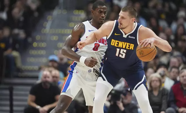 Denver Nuggets center Nikola Jokic, front, looks to pass the ball as Detroit Pistons center Jalen Duren defends in the first half of an NBA basketball game Saturday, Dec. 28, 2024, in Denver. (AP Photo/David Zalubowski)