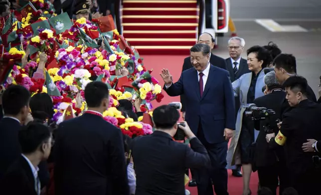 China's President Xi Jinping, center, greets children waving the flags of China and Macao, as his wife Peng Liyuan, right, looks on upon arrival at the airport in Macao, China, Wednesday, Dec. 18, 2024, ahead of celebrations marking the 25th anniversary of the casino city’s return to Chinese rule. (Eduardo Leal/Pool Photo via AP)