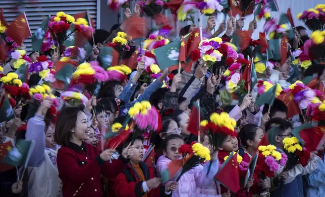 Children wave the flags of China and Macao prior to Chinese President Xi Jinping's arrival at the airport in Macao, China, Wednesday, Dec. 18, 2024, ahead of celebrations marking the 25th anniversary of the casino city’s return to Chinese rule. (Eduardo Leal/Pool Photo via AP)