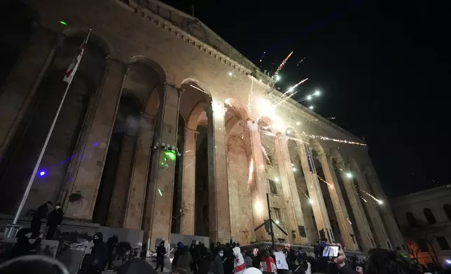 Demonstrators launch firecracker into the parliament's building during a rally to protest against the government's decision to suspend negotiations on joining the European Union in Tbilisi, Georgia, on Tuesday, Dec. 3, 2024. (AP Photo/Pavel Bednyakov)