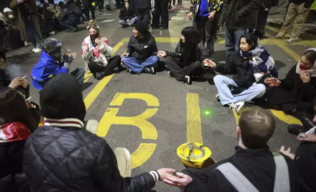 Demonstrators sit in the middle of a street rallying to continue protests against the government's decision to suspend negotiations on joining the European Union in Tbilisi, Georgia, early Tuesday, Dec. 3, 2024. (AP Photo/Zurab Tsertsvadze)