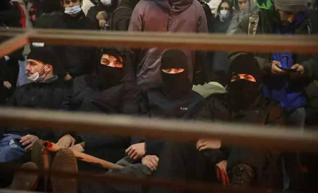 Demonstrators sit at a barricade rallying to continue protests against the government's decision to suspend negotiations on joining the European Union in Tbilisi, Georgia, early Tuesday, Dec. 3, 2024. (AP Photo/Zurab Tsertsvadze)