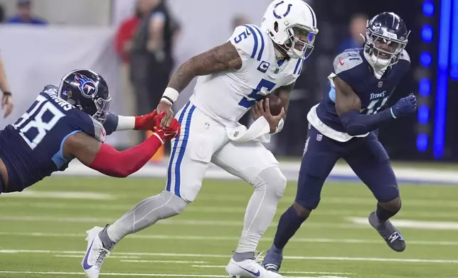 Indianapolis Colts quarterback Anthony Richardson (5) runs the ball past Tennessee Titans defensive tackle Jeffery Simmons (98) and linebacker Otis Reese IV (41) during the first half of an NFL football game Sunday, Dec. 22, 2024, in Indianapolis. (AP Photo/Michael Conroy)