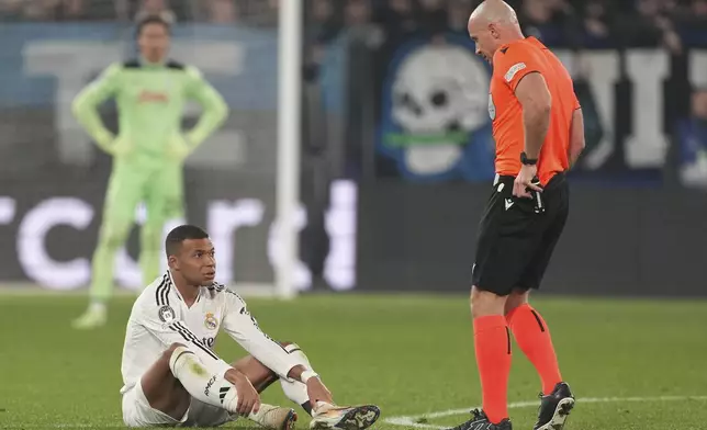 Real Madrid's Kylian Mbappe, left, talks with referee Szymon Marciniak during the Champions League opening phase soccer match between Atalanta and Real Madrid at the Bergamo's stadium, in Bergamo, Italy, Tuesday, Dec. 10, 2024. (AP Photo/Antonio Calanni)