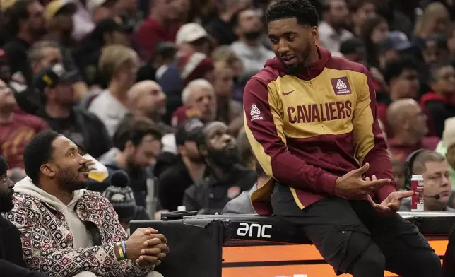 Cleveland Cavaliers guard Donovan Mitchell, right, talks with Cleveland Browns defensive end Myles Garrett, left, as he waits to return to the game in the first half of an NBA Cup basketball game against the Washington Wizards, Tuesday, Dec. 3, 2024, in Cleveland. (AP Photo/Sue Ogrocki)