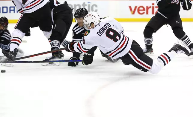 Chicago Blackhawks center Ryan Donato (8) shoots the puck as New Jersey Devils defenseman Dougie Hamilton (7) defends during the first period of an NHL hockey game, Saturday, Dec. 14, 2024, in Newark, N.J. (AP Photo/Noah K. Murray)