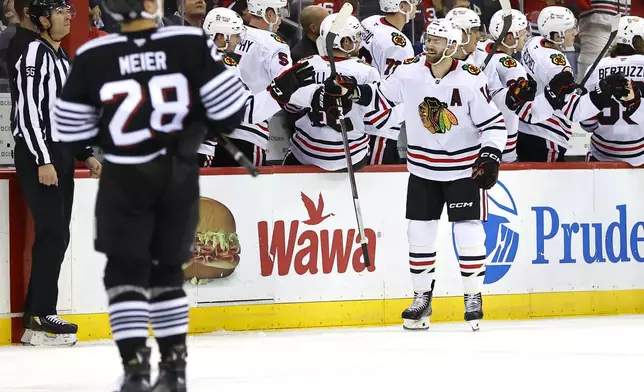 Chicago Blackhawks center Jason Dickinson (16) celebrates with teammates after scoring a goal against the New Jersey Devils during the second period of an NHL hockey game, Saturday, Dec. 14, 2024, in Newark, N.J. (AP Photo/Noah K. Murray)