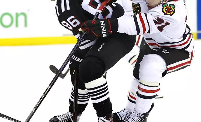 New Jersey Devils center Jack Hughes (86) and Chicago Blackhawks left wing Taylor Hall (71) battle for the puck during the second period of an NHL hockey game, Saturday, Dec. 14, 2024, in Newark, N.J. (AP Photo/Noah K. Murray)