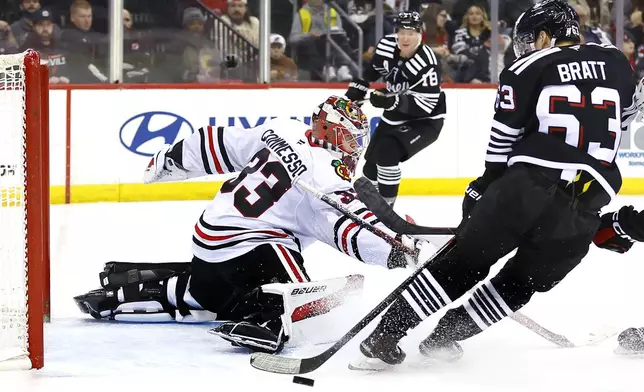 Chicago Blackhawks goaltender Drew Commesso (33) defends against New Jersey Devils left wing Jesper Bratt (63) during the second period of an NHL hockey game, Saturday, Dec. 14, 2024, in Newark, N.J. (AP Photo/Noah K. Murray)