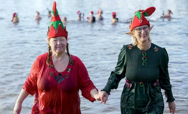 Members of the winter and ice swimming club 'Seehunde Berlin', (Berlin Seals), wearing Christmas-themed hats, walk into the water during the traditional annual Christmas swim on Christmas Day, at the Oranke Lake in Berlin, Wednesday, Dec. 25, 2024. (AP Photo/Ebrahim Noroozi)