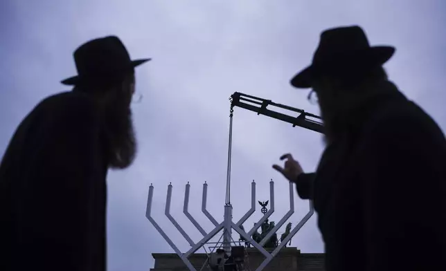 Rabbi Yehuda Teichtal, right, and Rabbi Shmuel Segal, left, watch the set-up of a giant Hanukkah Menorah by the Jewish Chabad Educational Center ahead of the Jewish Hanukkah holiday, in front of the Brandenburg Gate at the Pariser Platz in Berlin, Germany, Monday, Dec. 23, 2024. (AP Photo/Markus Schreiber)