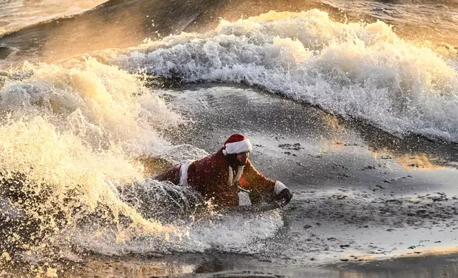 Carlos Hebert Plante, who boogie boards daily, dressed as Santa Claus hits the St-Lawrence River amid an air temperature of -14 degrees Celsius on Christmas Day, in Montreal, Wednesday, Dec. 25, 2024. (Bernard Brault /The Canadian Press via AP)