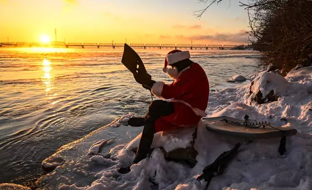 Carlos Hebert Plante, who boogie boards daily, dressed as Santa Claus gets ready to hit the St-Lawrence Riveramid an air temperature of -14 degrees Celsius on Christmas Day, in Montreal, Wednesday, Dec. 25, 2024. (Bernard Brault /The Canadian Press via AP)