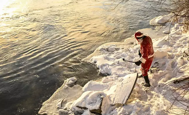 Carlos Hebert Plante, who boogie boards daily, dressed as Santa Claus gets ready to hit the St-Lawrence River amid an air temperature of -14 degrees Celsius on Christmas Day, in Montreal, Wednesday, Dec. 25, 2024. (Bernard Brault /The Canadian Press via AP)