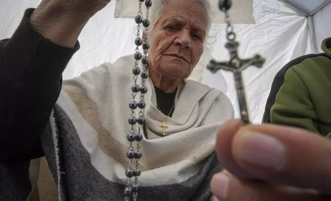 Amal Amouri shows a cross to the photographer at the tent she and her husband Tony Al-Masri, both Christians, share at the Muwassi tent camp near Khan Younis, Gaza Strip on Christmas Day Wednesday Dec. 25, 2024.(AP Photo/Abdel Kareem Hana)