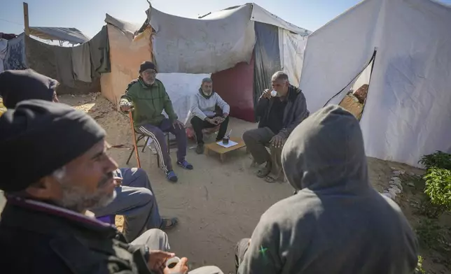 Tony Al-Masri, center left, sits with neighbours outside the tent he and his wife Amal Amouri, both Christians, share at the Muwassi tent camp near Khan Younis, Gaza Strip on Christmas Day Wednesday Dec. 25, 2024.(AP Photo/Abdel Kareem Hana)