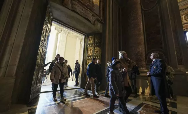 Faithful walk through the Holy Door of St.Peter's Basilica at the Vatican, Wednesday, Dec. 25, 2024, after it was opened by Pope Francis on Christmas Eve marking the start of the Catholic 2025 Jubilee. (AP Photo/Andrew Medichini)