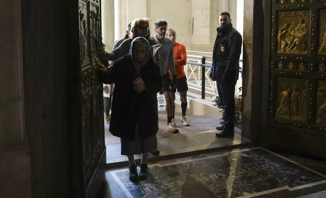 Faithful walk through the Holy Door of St.Peter's Basilica at the Vatican, Wednesday, Dec. 25, 2024, after it was opened by Pope Francis on Christmas Eve marking the start of the Catholic 2025 Jubilee. (AP Photo/Andrew Medichini)