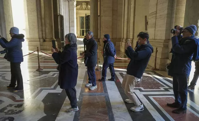 Faithful take photos as they arrive to walk through the Holy Door of St. Peter's Basilica at the Vatican, Wednesday, Dec. 25, 2024, after it was opened by Pope Francis on Christmas Eve marking the start of the Catholic 2025 Jubilee. (AP Photo/Andrew Medichini)