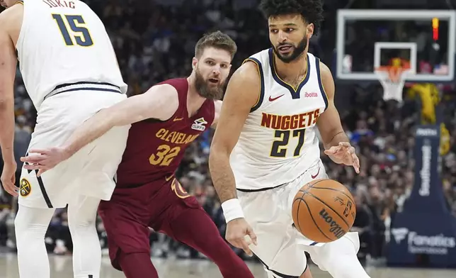 Denver Nuggets guard Jamal Murray, front, drives past Cleveland Cavaliers forward Dean Wade in the first half of an NBA basketball game Friday, Dec. 27, 2024, in Denver. (AP Photo/David Zalubowski)