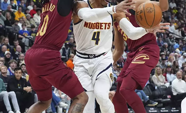 Denver Nuggets guard Russell Westbrook, center, passes the ball as he drives between Cleveland Cavaliers guard Darius Garland, left, and center Jarrett Allen in the first half of an NBA basketball game Friday, Dec. 27, 2024, in Denver. (AP Photo/David Zalubowski)