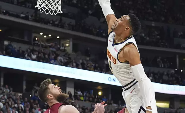 Denver Nuggets guard Russell Westbrook, right, tries to dunk the ball for a basket over Cleveland Cavaliers forward Dean Wade in the first half of an NBA basketball game Friday, Dec. 27, 2024, in Denver. (AP Photo/David Zalubowski)