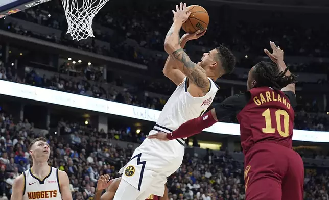 Denver Nuggets forward Michael Porter Jr., left, is fouled as he drives to the basket by Cleveland Cavaliers guard Darius Garland in the first half of an NBA basketball game Friday, Dec. 27, 2024, in Denver. (AP Photo/David Zalubowski)