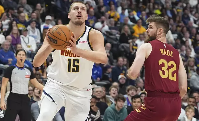 Denver Nuggets center Nikola Jokic, left, drives to the basket past Cleveland Cavaliers forward Dean Wade in the first half of an NBA basketball game Friday, Dec. 27, 2024, in Denver. (AP Photo/David Zalubowski)