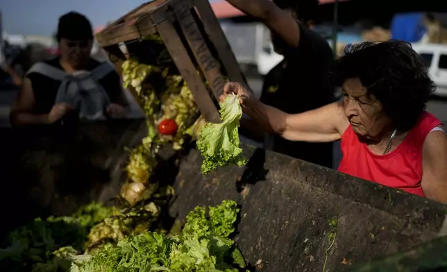 FILE - A woman culls through produce discarded by vendors at a market on the outskirts of Buenos Aires, Argentina, Jan. 10, 2024. Argentine President Javier Milei has scrapped price controls and slashed subsidies, causing prices to skyrocket in a country that already had among the world's highest inflation rates. (AP Photo/Natacha Pisarenko, File)