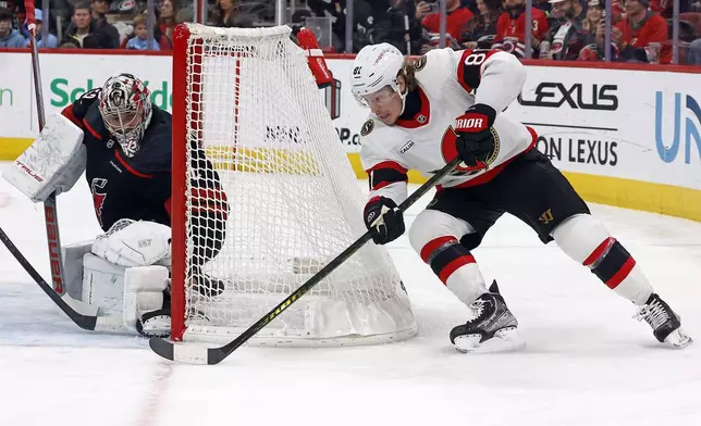 Ottawa Senators' Adam Gaudette (81) carries the puck around the net to shoot at Carolina Hurricanes goaltender Pyotr Kochetkov (52) during the first period of an NHL hockey game in Raleigh, N.C., Friday, Dec. 13, 2024. (AP Photo/Karl B DeBlaker)