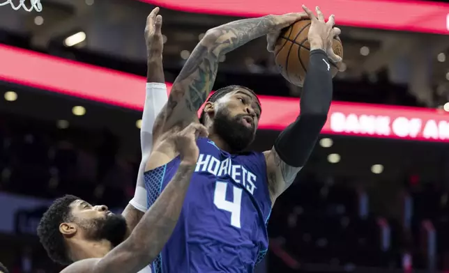 Charlotte Hornets center Nick Richards (4) pulls down an offensive rebound against Philadelphia 76ers forward Paul George during the first half of an NBA Cup basketball game in Charlotte, N.C., Tuesday, Dec. 3, 2024. (AP Photo/Nell Redmond)