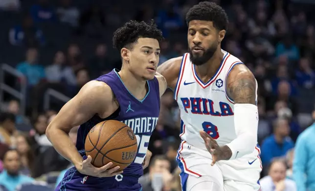 Charlotte Hornets guard KJ Simpson, left, drives against Philadelphia 76ers forward Paul George during the first half of an NBA Cup basketball game in Charlotte, N.C., Tuesday, Dec. 3, 2024. (AP Photo/Nell Redmond)